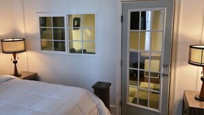 Un dormitorio con una cama, dos lámparas de noche, una ventana y una puerta.