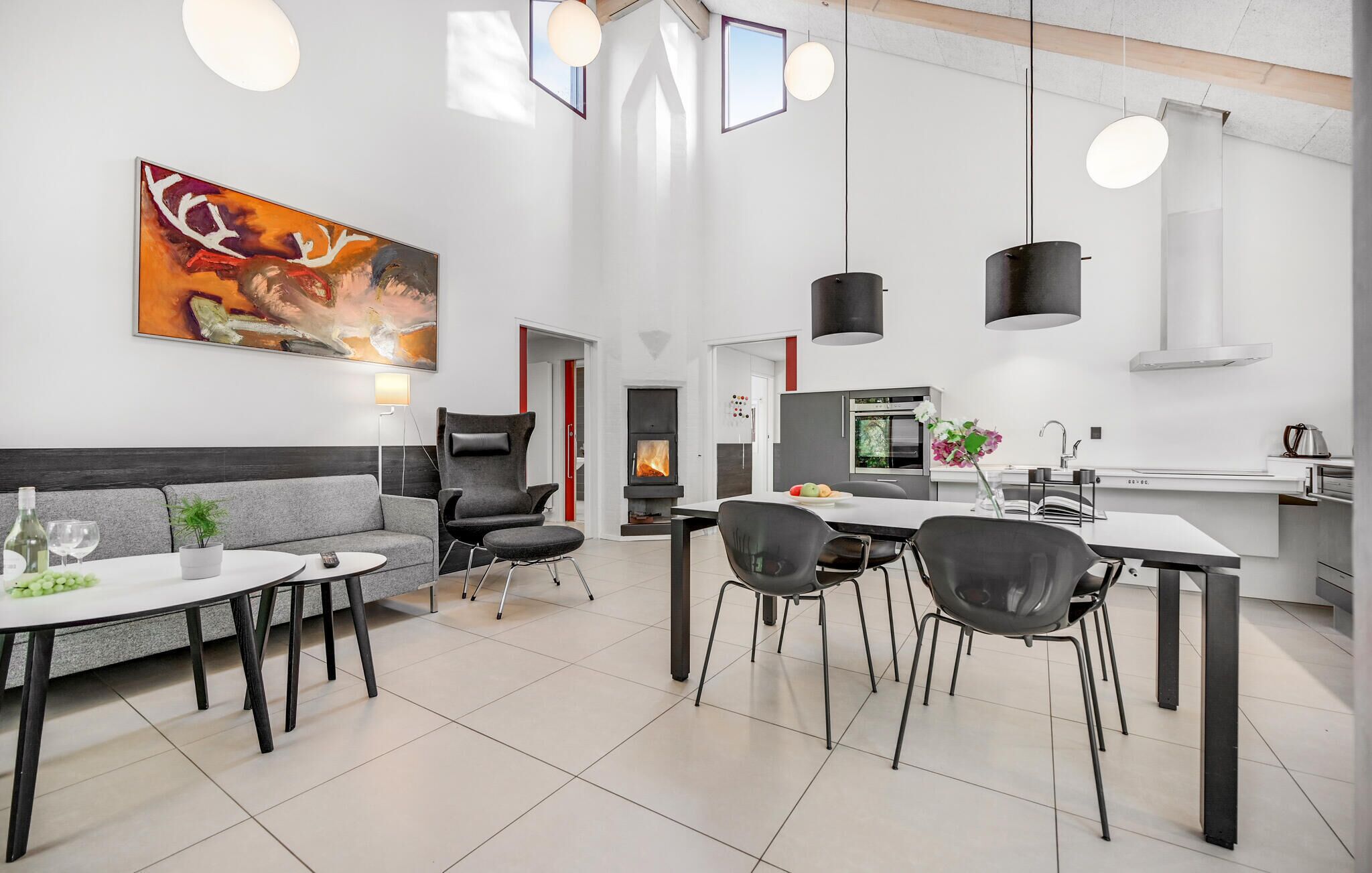 Une cuisine moderne avec un îlot central, un coin repas comprenant un canapé et des chaises, et un grand tableau abstrait accroché au mur.