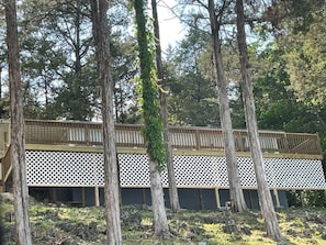 A wooden deck with lattice railings, surrounded by tall trees.