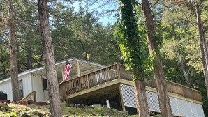 Une cabane dotée d’une terrasse en bois et d’un porche abrité, entourée d’arbres.