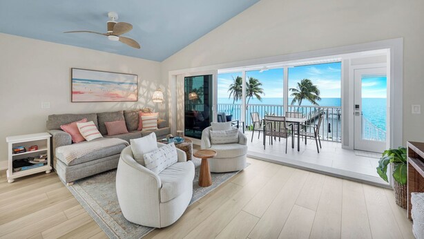 A spacious living room with a balcony overlooking the ocean, featuring a sofa, armchairs, and a dining area. - Captiva Hide A Way 2D- Luxury Captiva Condo, Everything You Need! (Captiva)