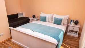 Un dormitorio con una cama, mesitas de noche, un mueble auxiliar, un sofá y un pequeño archivador con la etiqueta “Smile”.