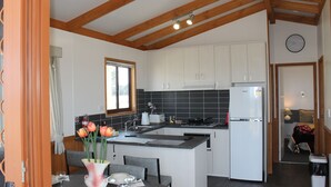 Una cocina moderna con armarios blancos, una isla central y un comedor con una mesa dispuesta para dos.