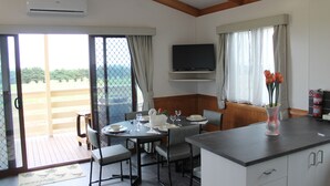 Un comedor con una mesa preparada para cuatro personas, un televisor montado sobre la mesa, y vistas al exterior a través de un ventanal corredera.