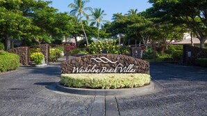 A sign for Waikoloa Beach Villas with a stone archway and a landscaped garden.