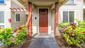 A house entrance with a wooden door, a porch with a roof, and a mailbox.