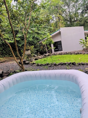 An inflatable pool surrounded by greenery and a modern building.