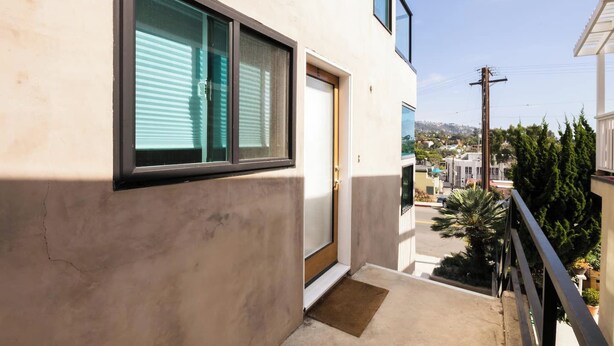 Un balcón con vistas a una zona residencial, una puerta y una ventana con persianas.