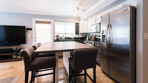 Una cocina moderna con una isla central, electrodomésticos de acero inoxidable y un televisor de pantalla plana.