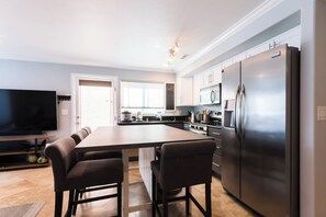 Una cucina moderna con isola centrale, elettrodomestici in acciaio inossidabile e televisore a schermo piatto.