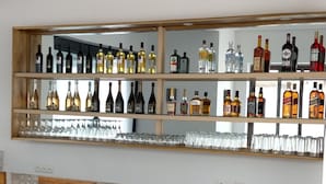 A bar area with wooden chairs and a shelf of various liquor bottles. - MARBELLA HOTEL (Lomé)