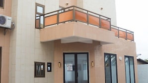 A modern building with a flat facade, large windows, and a balcony with orange railings. - MARBELLA HOTEL (Lomé)