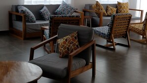 A spacious room with a sofa set, wooden chairs, and a round table. - MARBELLA HOTEL (Lomé)