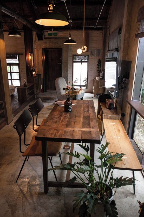 A rustic dining area with a wooden table, chairs, pendant lights, and a large window. - Twilight Forest (New Taipei City)