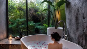 A bathtub with rose petals, a candle, and a plant on a windowsill. - Twilight Forest (New Taipei City)