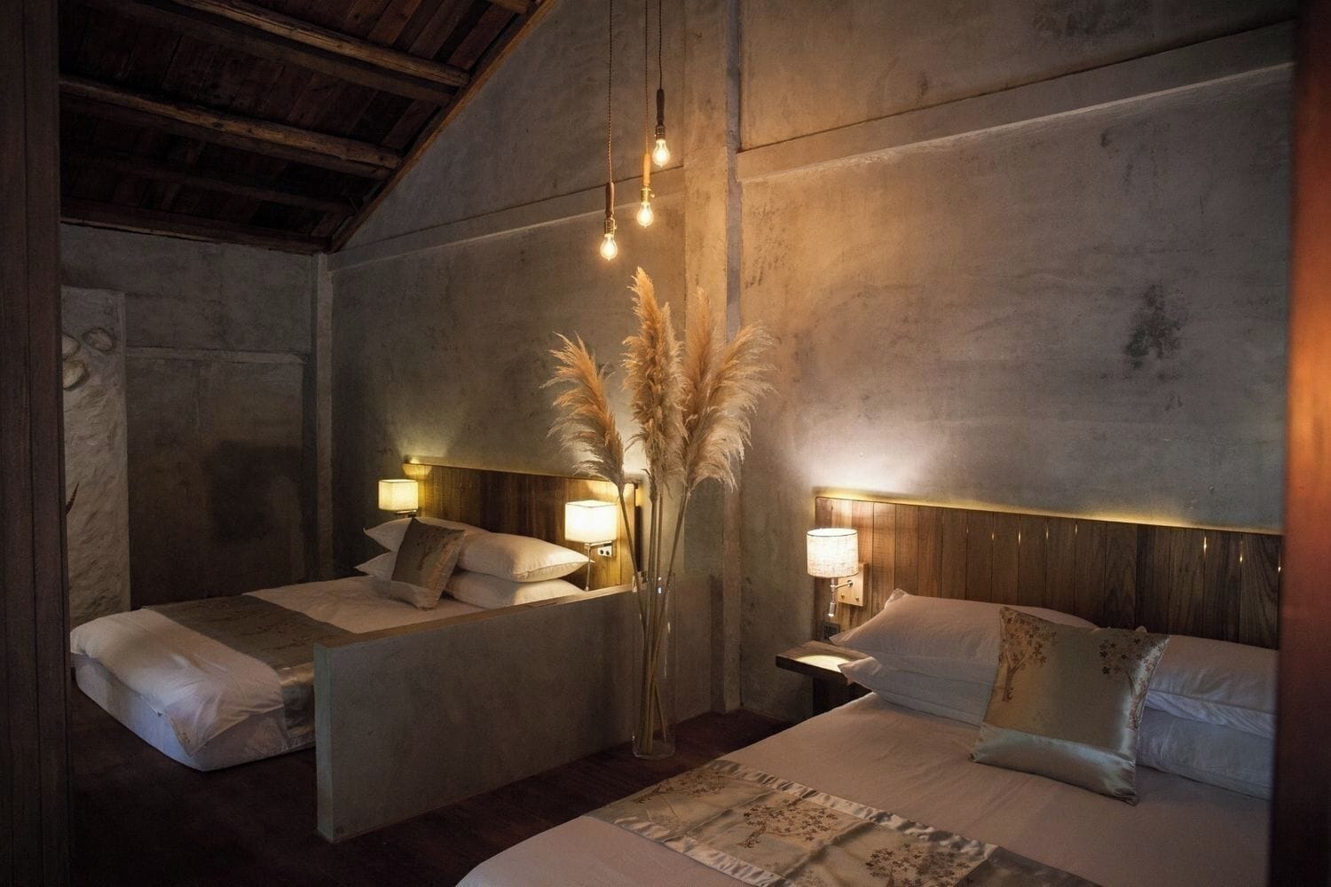 Een kamer met twee bedden, een houten plafond en wandlampen.