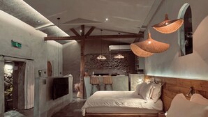 A modern hotel room with a large bed, a stone wall, and a fireplace. - Twilight Forest (New Taipei City)