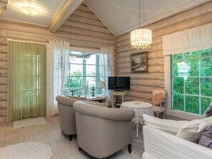 A cozy room with a television, two sofas, a table, and a large window with a view of greenery. - Torniniemi by Interhome (Punkaharju)