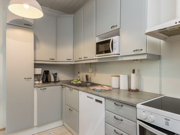 A compact kitchen with white cabinets, a microwave, a coffee maker, and a dishwasher. - Torniniemi by Interhome (Punkaharju)