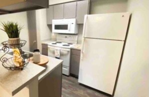 Kitchen area with modern appliances, including a microwave, stove, and refrigerator, and a small potted plant.