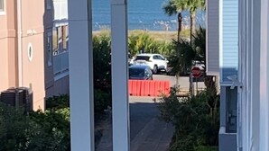 En kystvej med et stopskilt, parkerede biler og udsigt til havet.