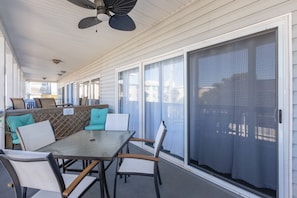 Une terrasse extérieure avec une table et des chaises, un ventilateur de plafond et une porte-fenêtre coulissante.