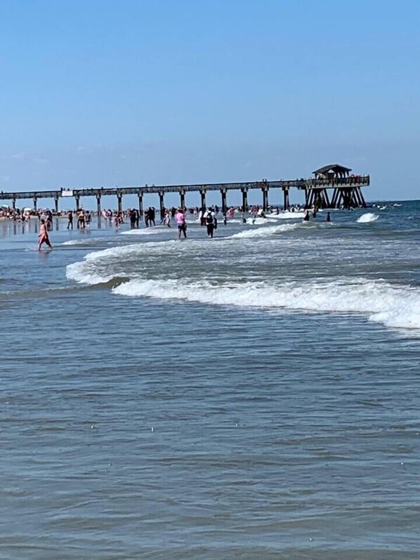 A pier extending into the sea with people walking along it. - Sandy Toes Abode 2bd/2ba Condo 500ft from Beach (Tybee Island)