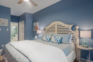 A bedroom with a bed, a nightstand, a lamp, and a ceiling fan. - Sandy Toes Abode 2bd/2ba Condo 500ft from Beach (Tybee Island)