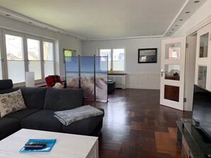 A spacious living room with a grey sofa, a white coffee table, and a TV stand. - Watzek Vacation Apartment (Grömitz)