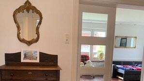 Una habitación con un armario de madera, un espejo y una puerta que da a otra habitación con una cama y una ventana.
