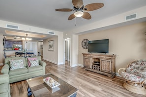 A spacious living room with a sofa, coffee table, and a TV on a wooden cabinet.