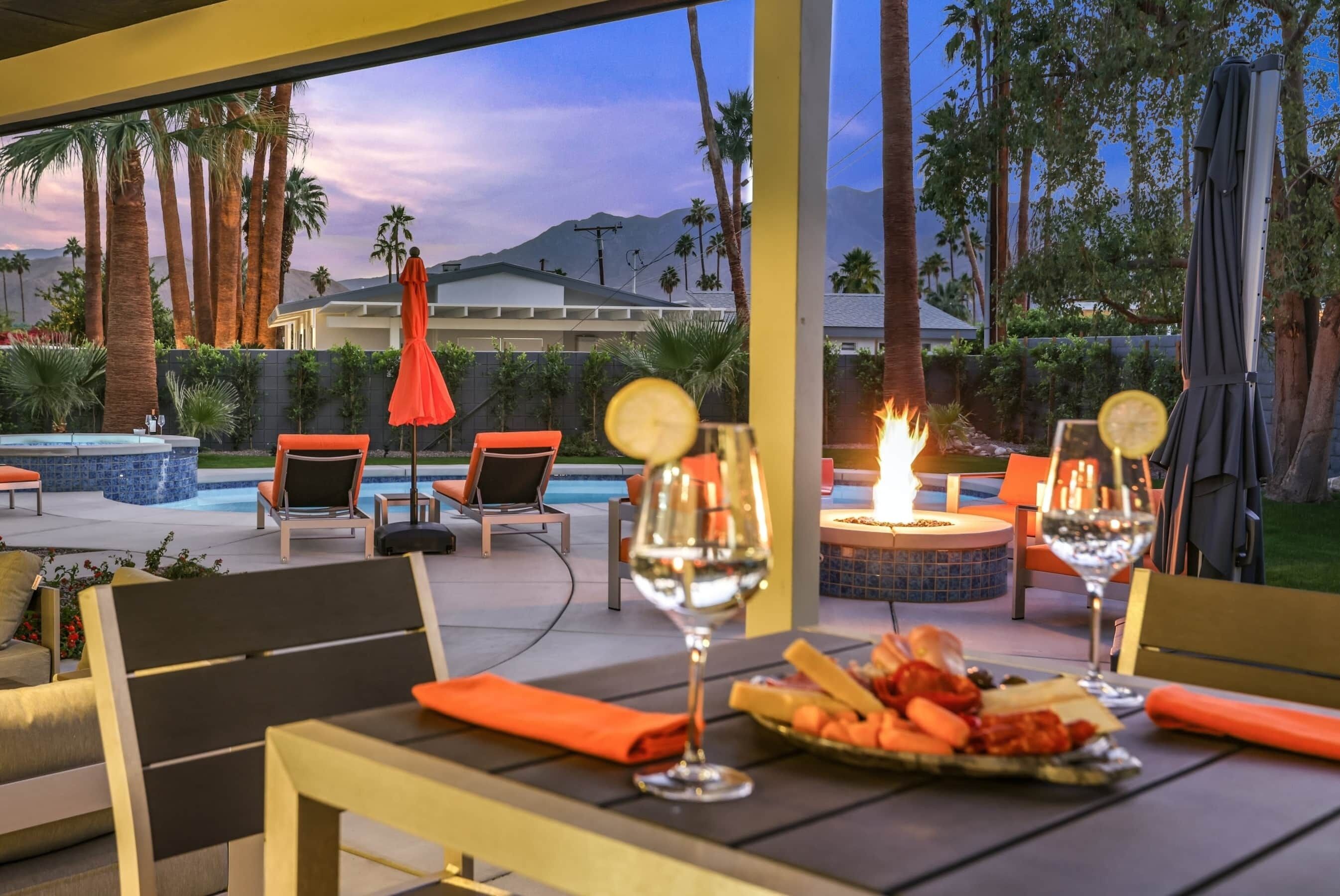 An outdoor patio with seating, a fire pit, and a pool view.