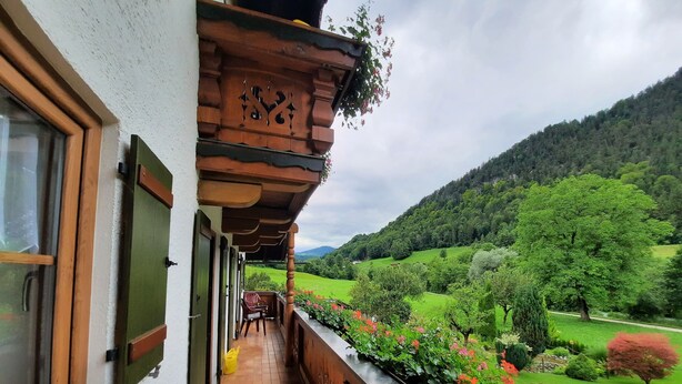A balcony with a view of a green valley and mountains.