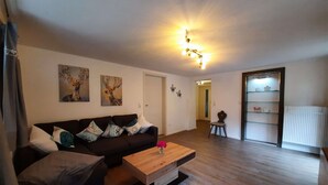 A living room with a brown sofa, a wooden coffee table, and two wall-mounted paintings.