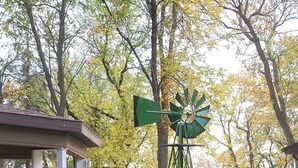 Un kiosque rustique avec un moulin à vent dans un jardin.