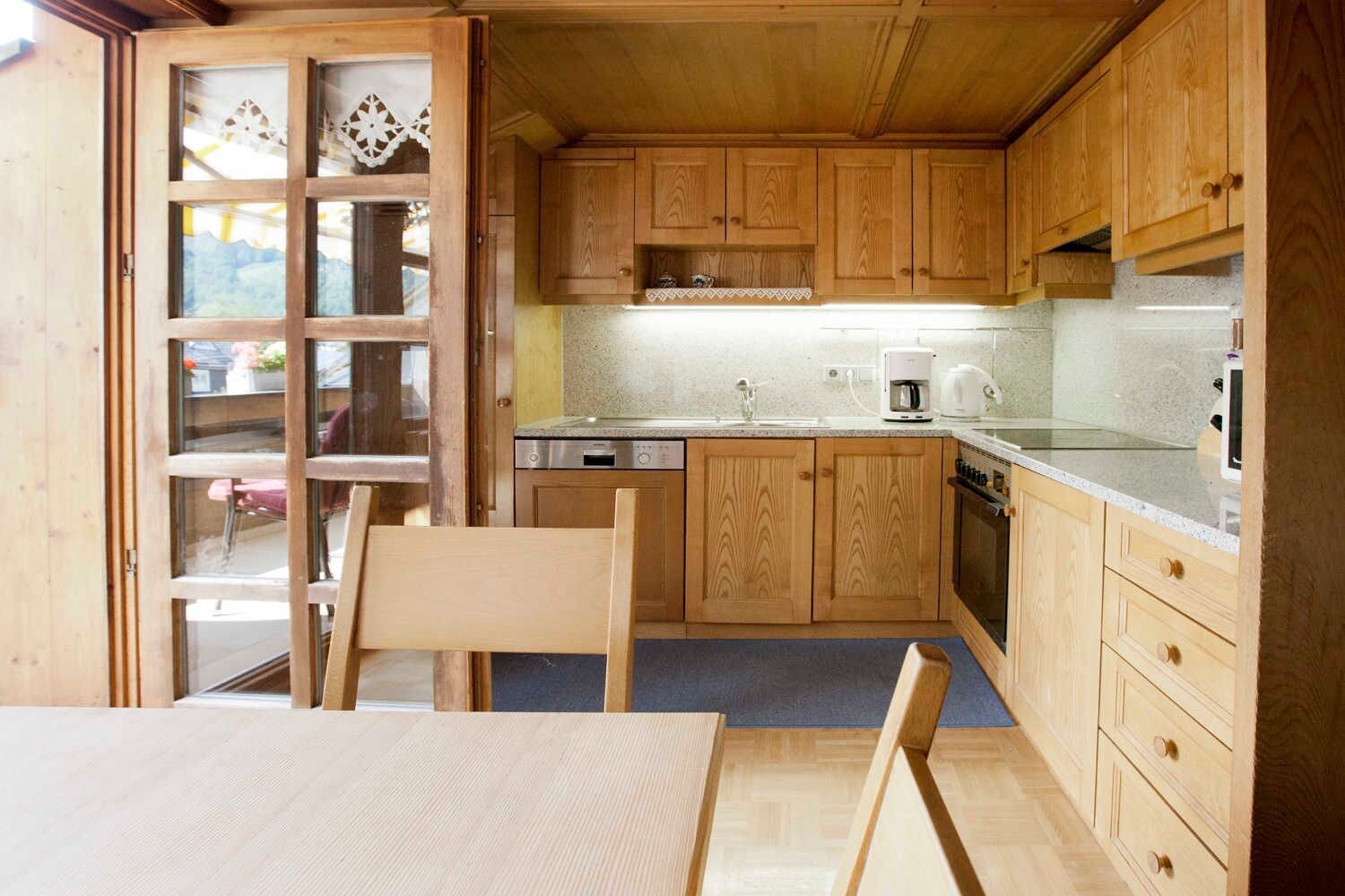 A wooden interior with a kitchen, dining area, and a view through a glass door.