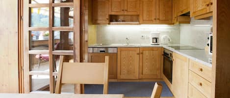 A wooden interior with a kitchen, dining area, and a view through a glass door.