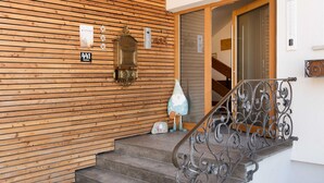 Pared exterior de madera con un buzón, un buzón pequeño y un cartel con el número '441'.