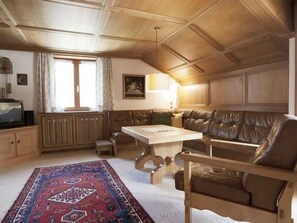 Una habitación con techo de madera, un sofá, una mesa y un tapete estampado.