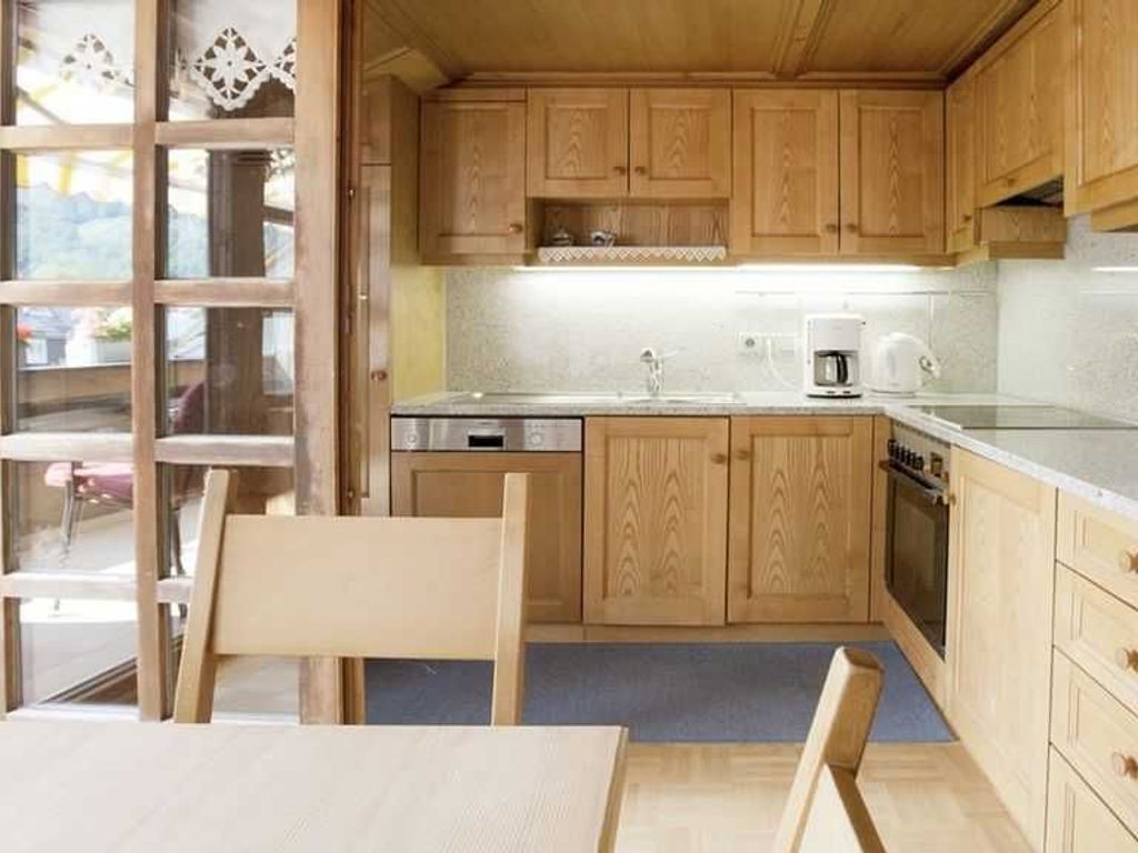 A kitchen with wooden cabinets, a sink, a dishwasher, and a stove.