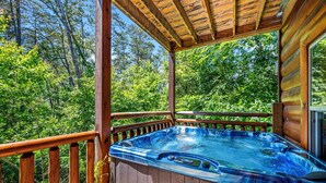 A hot tub on a wooden deck with a view of a forest. - Summer Offer • 5 King Suites • Games • Pool Access (Sevierville)