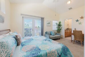 A bedroom with a bed, a balcony, a dining area, and a bathroom.