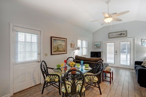 A dining area with a glass table, chairs, and a ceiling fan.
