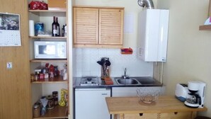 A compact kitchen with wooden cabinets, a microwave, a sink, and a coffee maker.