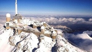 A snow-covered mountain with a large observatory and a tall tower.