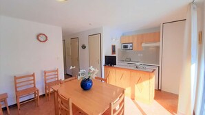 Un espacio habitable pequeño con comedor, kitchenette y baño reducido.