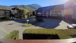 Un estacionamiento con un edificio al fondo, rodeado de montañas.