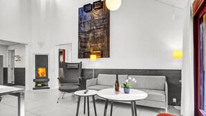 Ein modernes Interieur mit Kamin, grauem Sofa, runden Tischen und einem roten Sessel.