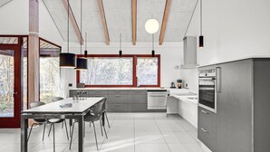 Eine moderne Küche mit Essbereich, ausgestattet mit einem großen Fenster, Einbaugeräten und einem minimalistischen Design.