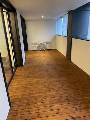 A room with a wooden floor, a small table with two chairs, and a window.